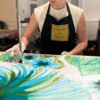 Pinceau appliquant des couleurs sur un tissu de soie tendu, dans l’atelier de peint-main Bochier Soieries