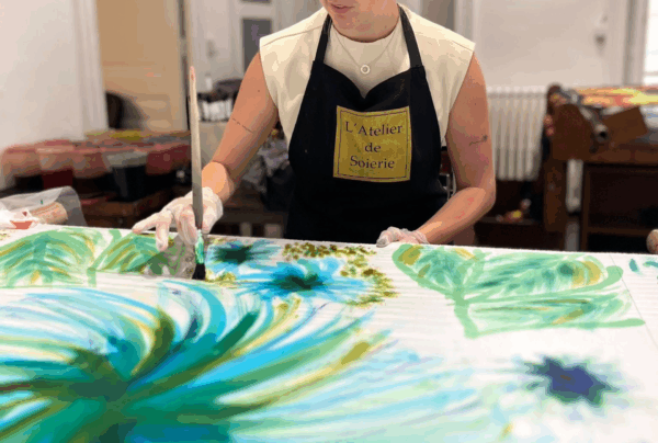 Pinceau appliquant des couleurs sur un tissu de soie tendu, dans l’atelier de peint-main Bochier Soieries