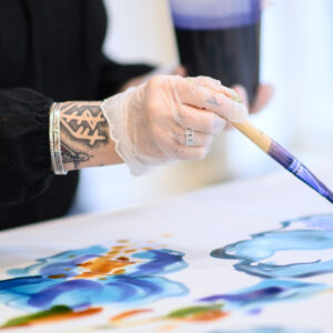 Gros plan sur la technique de peinture sur soie avec pinceau et couleurs cuisinées lors de l’atelier créatif