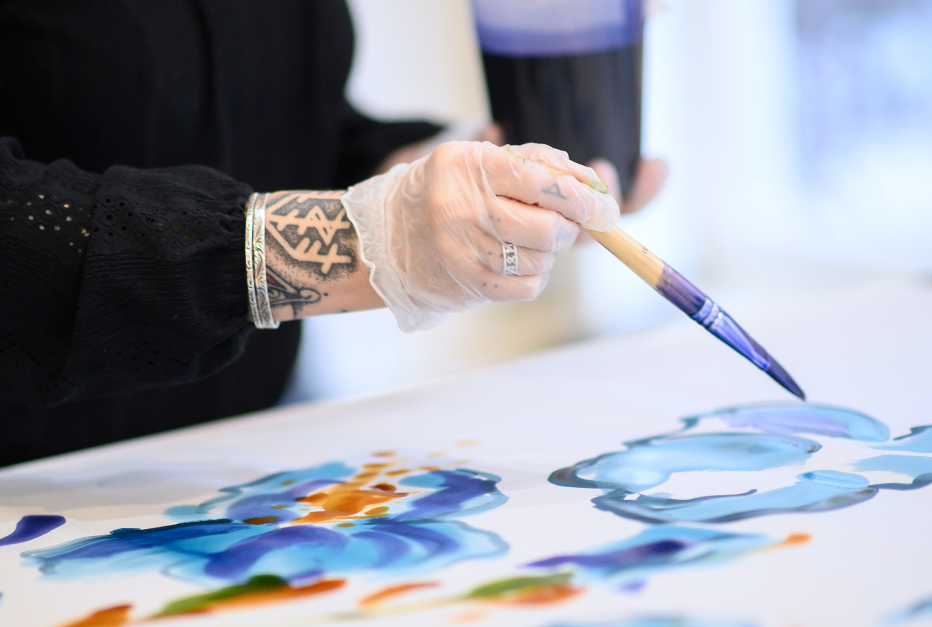 Gros plan sur la technique de peinture sur soie avec pinceau et couleurs cuisinées lors de l’atelier créatif